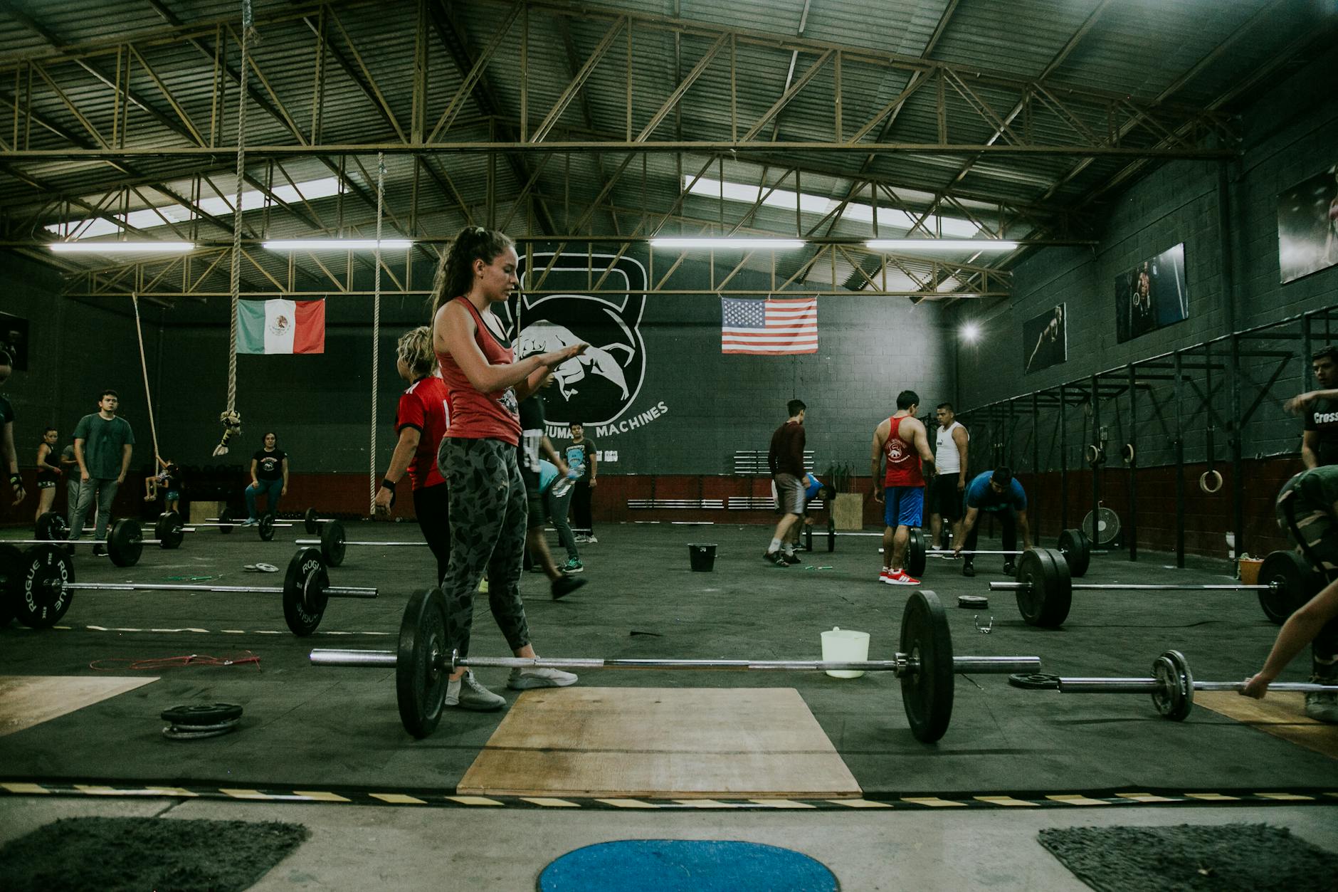 Dorośli podczas treningu CrossFit z ciężarami w siłowni w stylu industrialnym