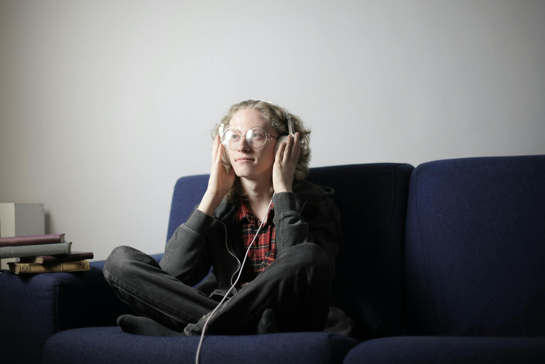 Audiobooki dla młodzieży na platformach streamingowych: co warto dodać do playlisty Nastolatek w słuchawkach słucha audiobooka na kanapie w salonie