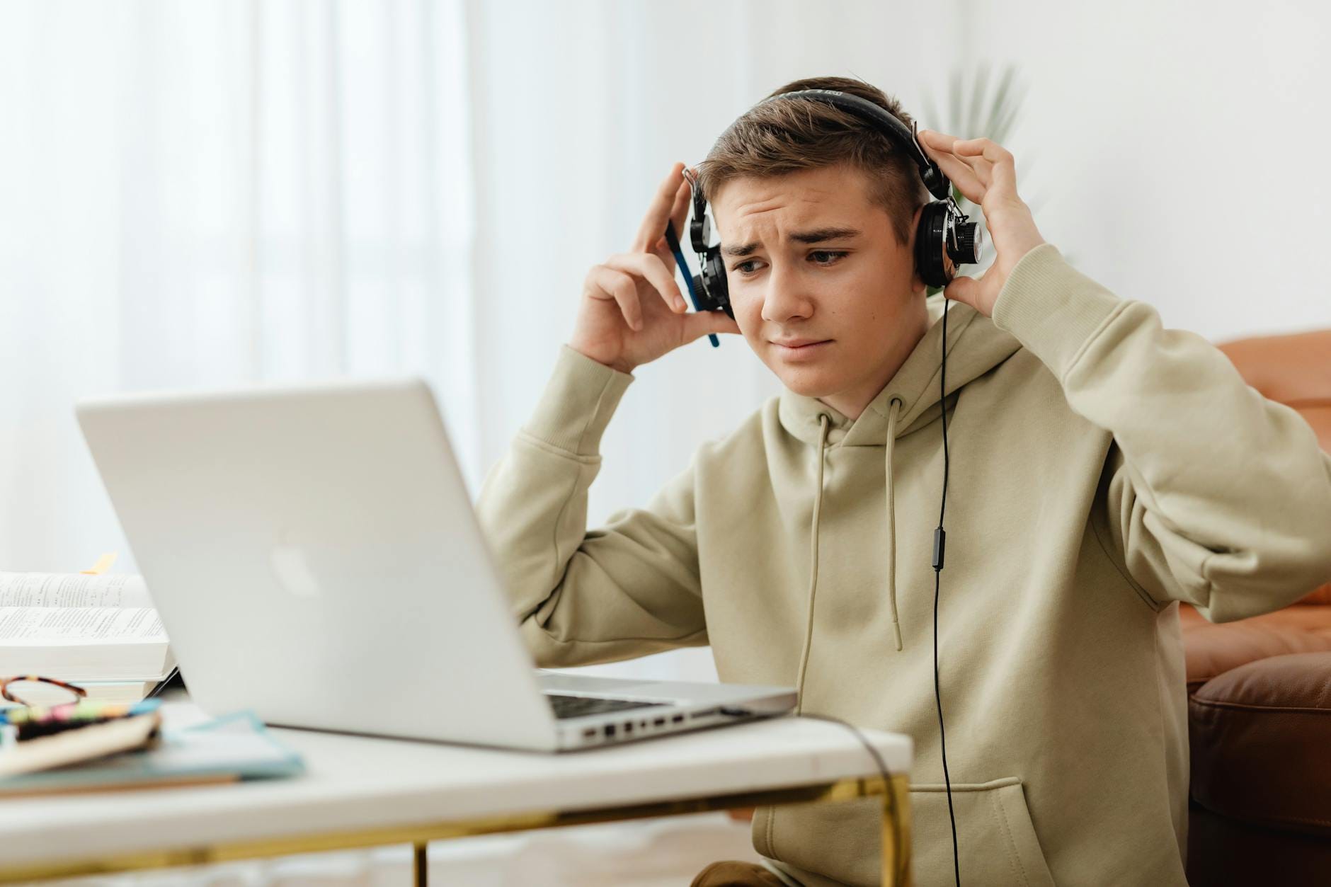Nastolatek w słuchawkach słucha audiobooka przy laptopie w domu