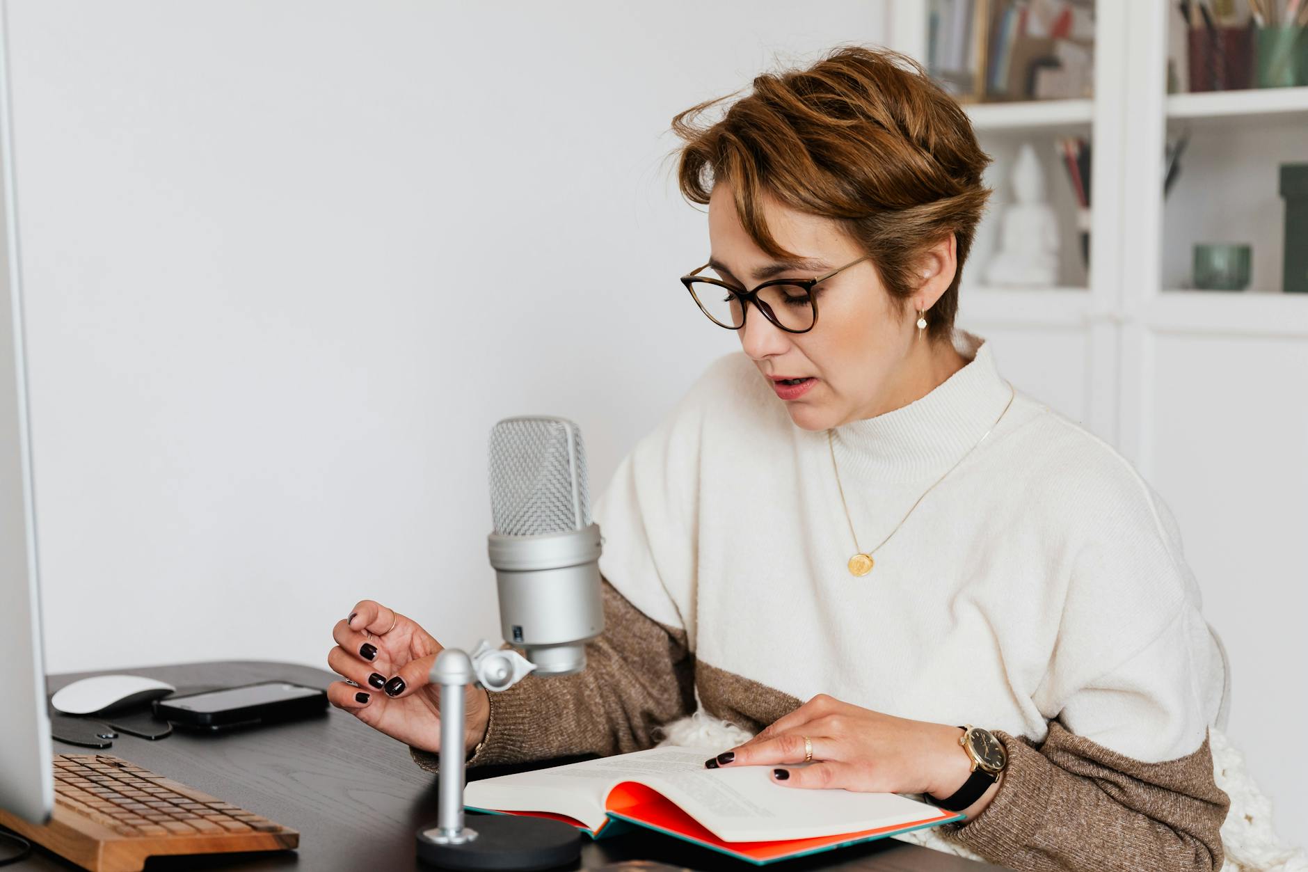 Lektorka w okularach nagrywa audiobook przy mikrofonie w domowym studiu